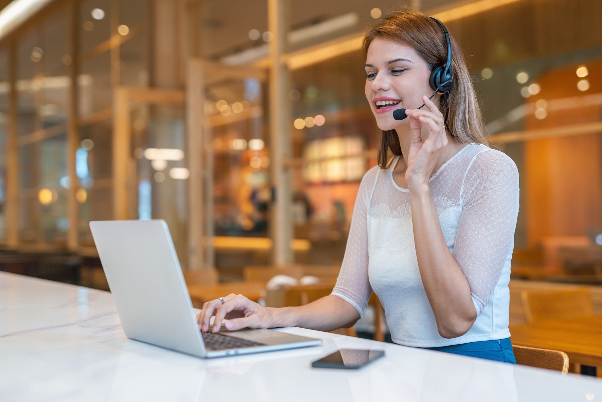 Beautiful mixed caucasian female customer service support staff working from a workspace with cafe